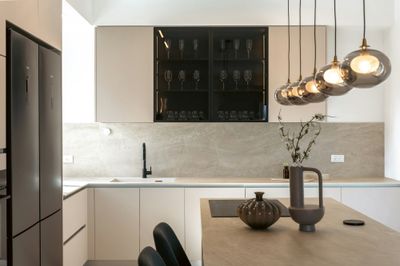 Modern open-plan kitchen with three pendant lights suspended over a white island worktop.